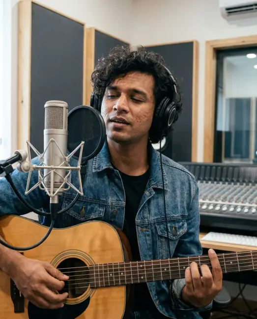 A musician playing an acoustic guitar in a small home studio